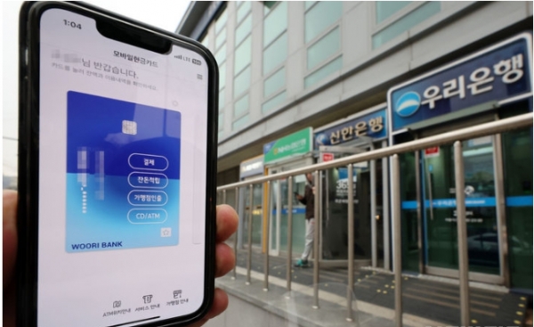 금융정보화추진협의회는 금융결제원 및  17개 국내은행과 함께 스마트폰 기종의 제한 없이 모바일현금카드 앱 및 모바일뱅킹 앱을 이용해 은행권 현금자동입출금기(ATM) 입출금을 가능하도록 하는 'QR코드 방식의 ATM 입출금 서비스'를 개시한다고 밝혔다. 사진은 6일 서울 시내의 한 ATM 부스와 모바일현금카드 앱 화면 모습. 2023.12.06